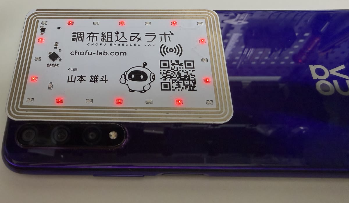 Android スマホの背面に名刺基板を重ねると、外周の赤い LED が光っている
