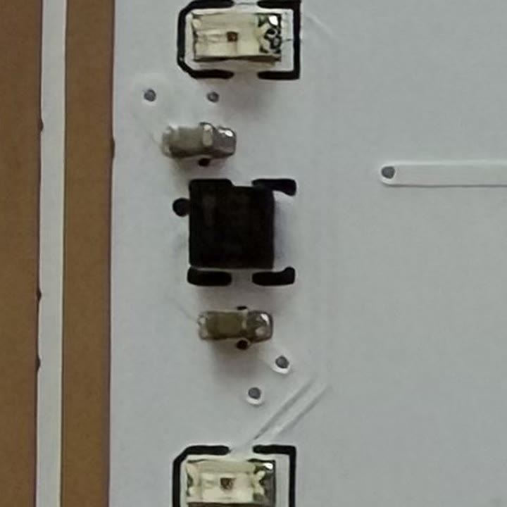 表面の左上の拡大。上下に LED、中央に黒い NFC チップ、その上と下に小さなコンデンサ